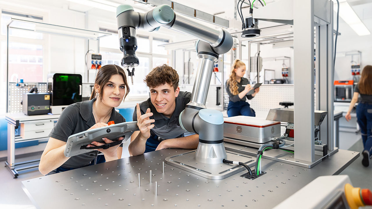 Zwei junge Menschen steuern ein Gerät in der Produktion