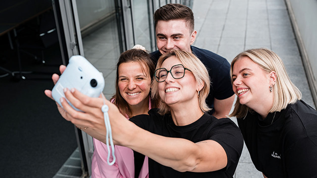 Selfie von vier jungen Menschen, die in die Kamera lächeln