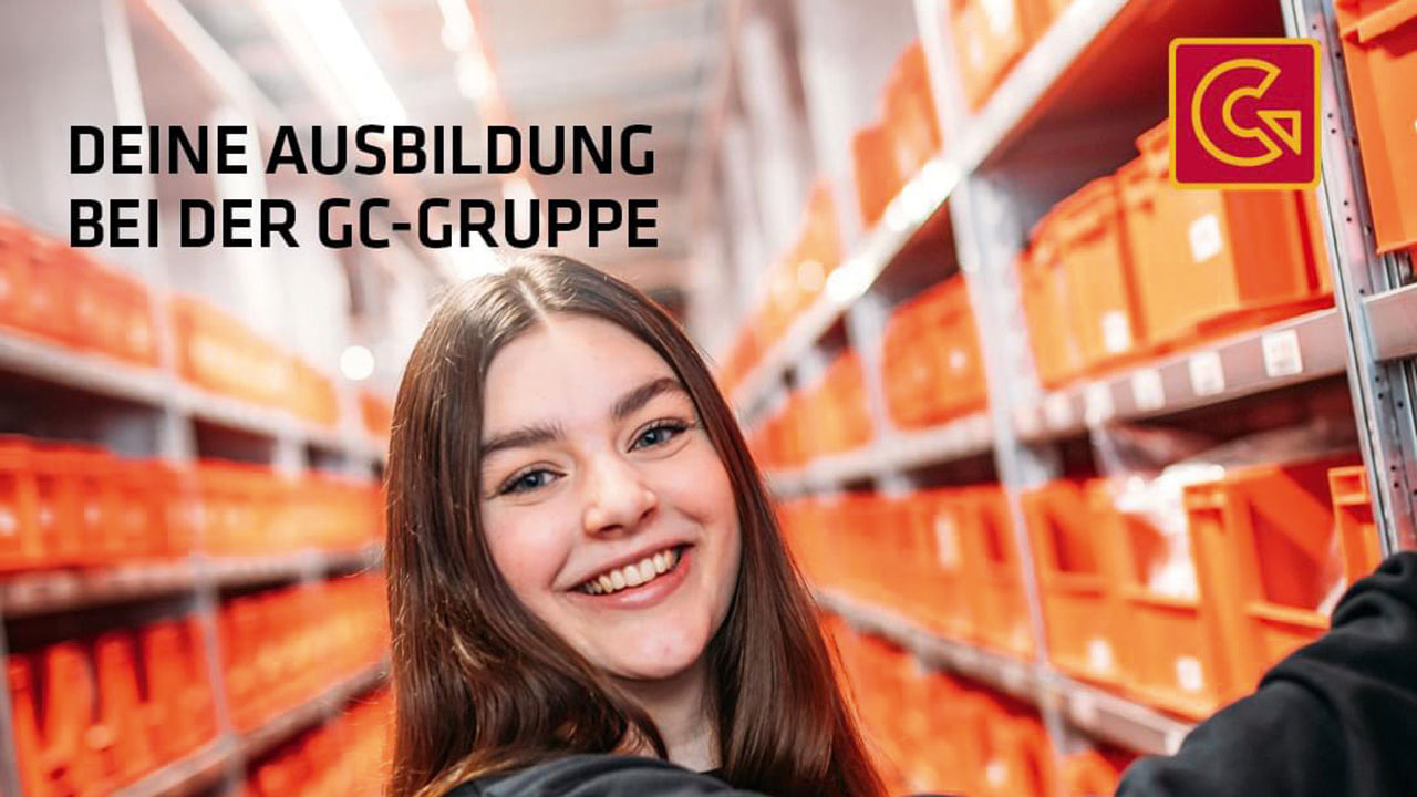 Junge lächelnde Person vor Lagerregalen mit roten Boxen