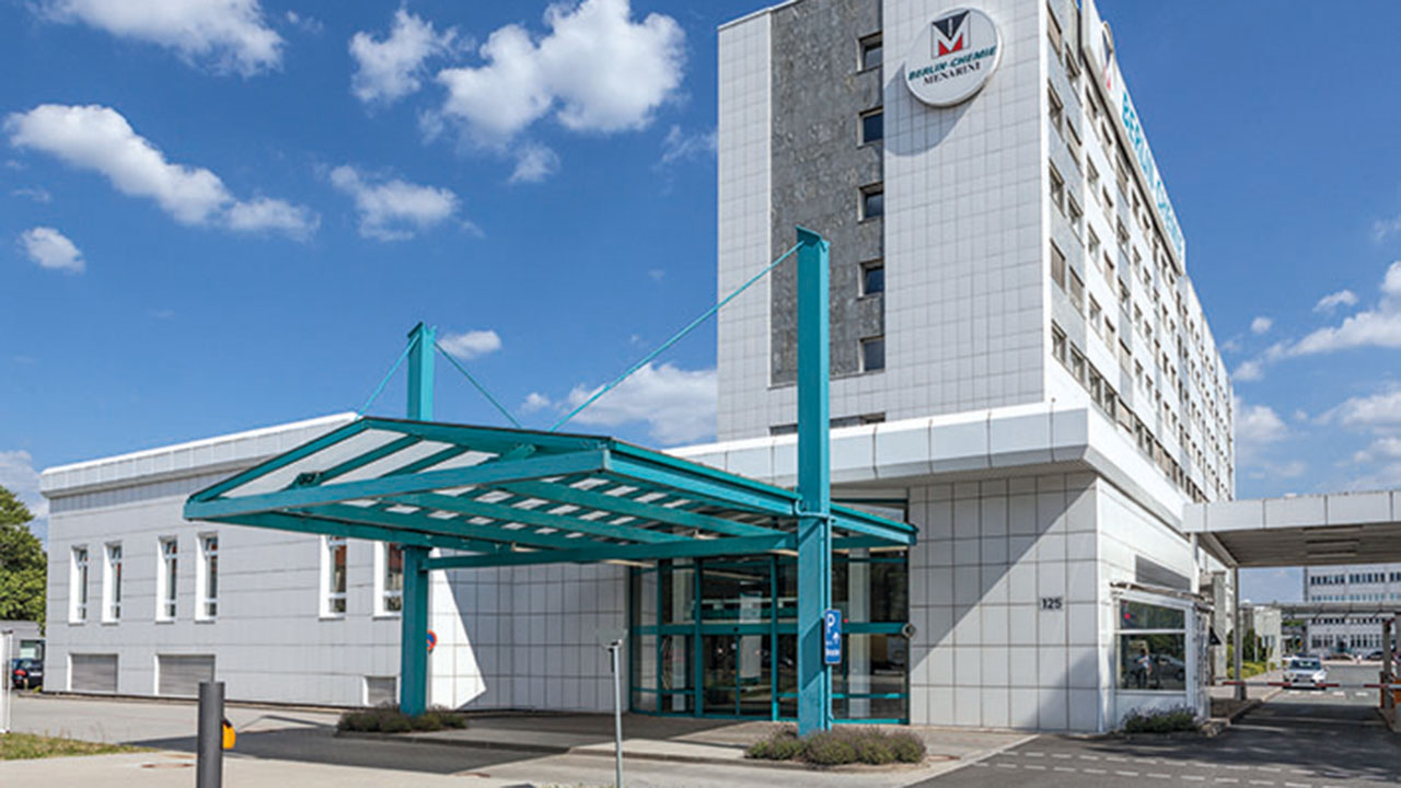 Gebäude der Berlin-Chemie AG bei blauem Himmel mit ein paar weißen Wolken im Hintergrund