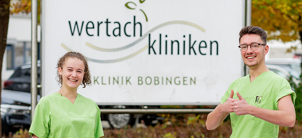 Zwei Personen vor dem Schild der Wertachkliniken