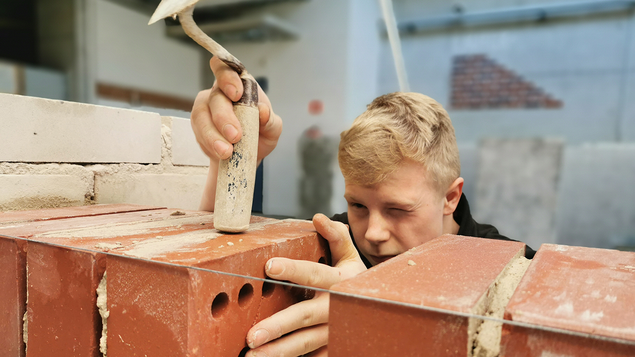 Eine Person arbeitet an einer Mauer. 