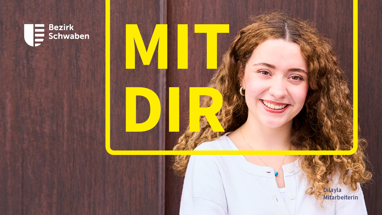 Porträt einer lächelnden Frau vor einer Holztür. Gelbe Gestaltungselemente und der Schriftzug „MIT DIR“ rahmen das Foto ein; oben links steht das Logo „Bezirk Schwaben“.