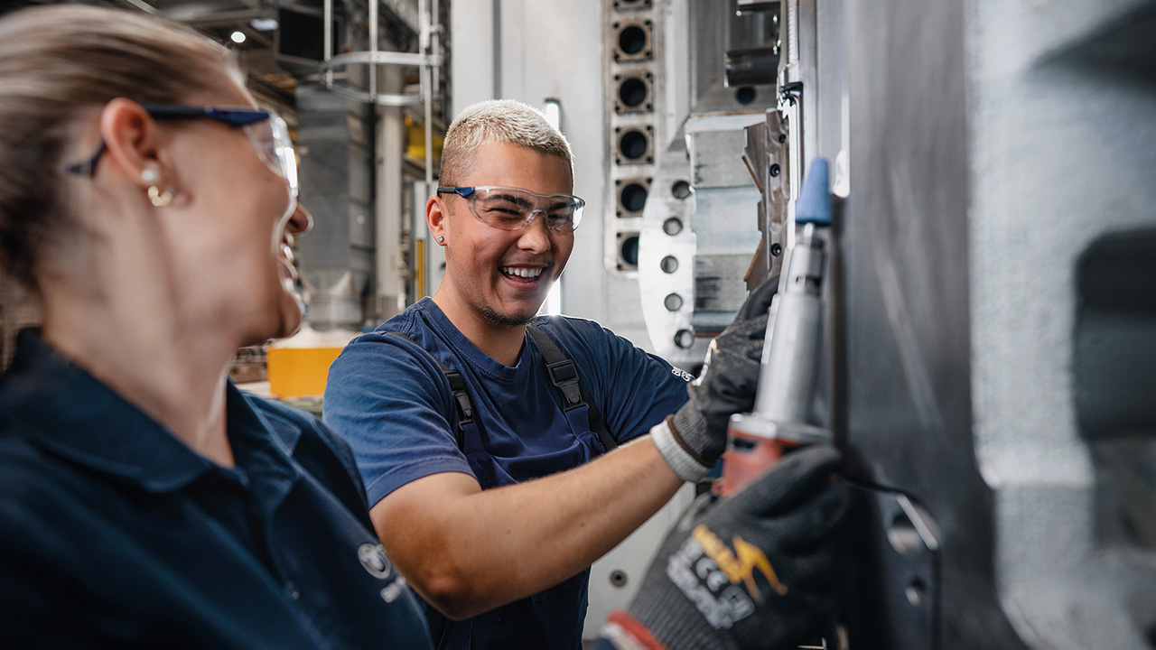 Zwei Menschen an einer Maschine die zusammen lachen