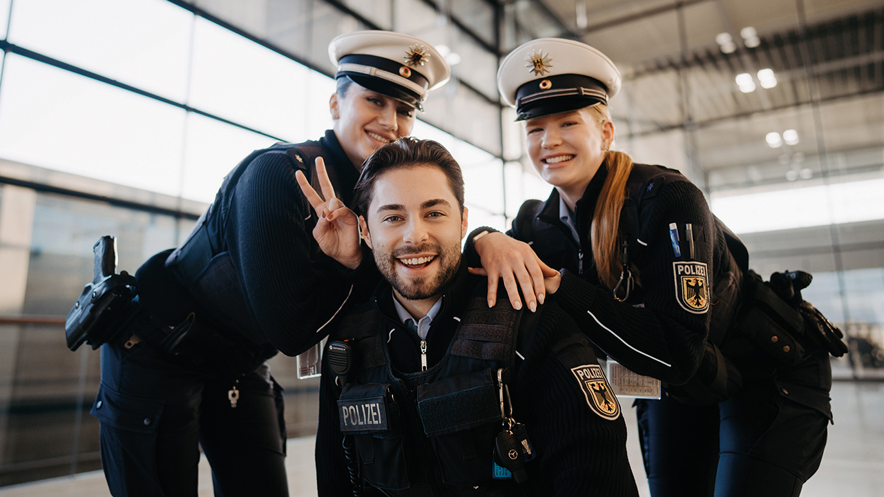 3 junge Polizeibeamte in Uniformen schauen freundilch in die Kamera.
