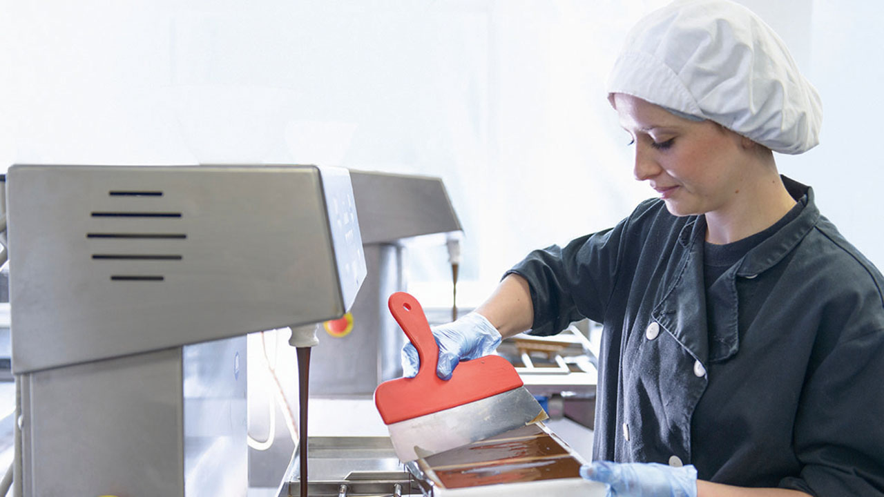 Person in Arbeitskleidung bei der Herstellung von Schokolade