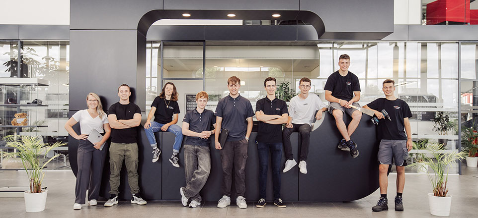 Personengruppe sitzt in einem Foyer auf einem großen, schwarzen C.