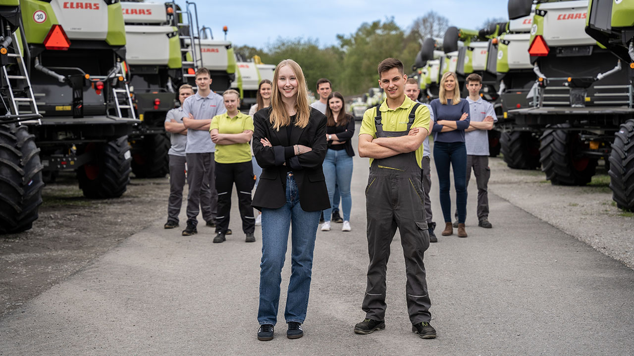 Personengruppe steht V-förmig vor verschiedenen Maschinen von CLAAS.