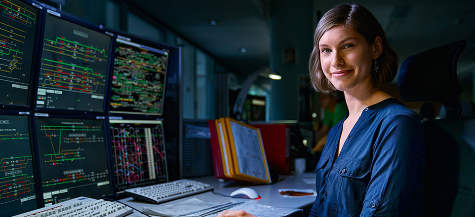 Person am Schreibtisch mit mehreren Monitoren. 
