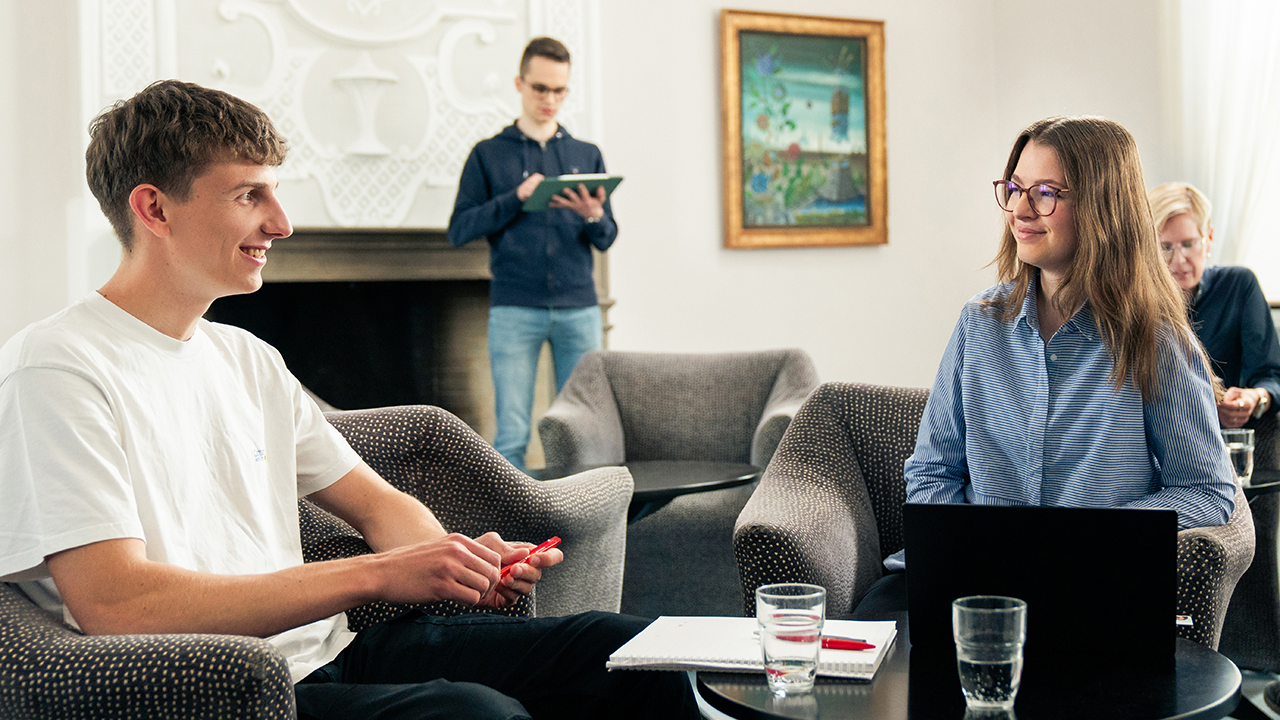 Zwei Menschen sitzen auf Sesseln und lächeln sich an