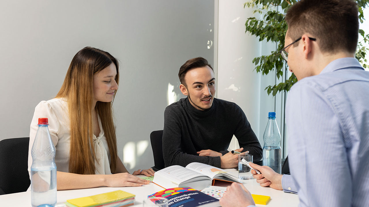 Drei junge Personen am Tisch im Gespräch