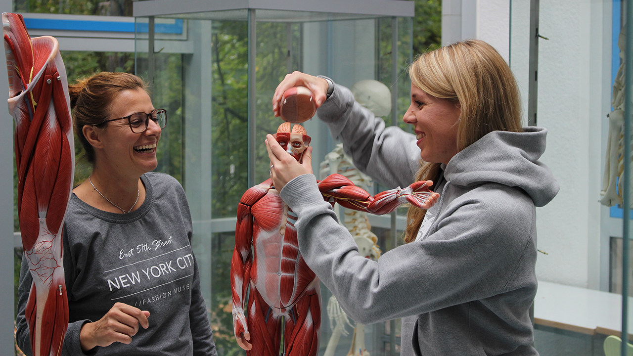 Zwei Frauen stehen vor einer Studienpuppe