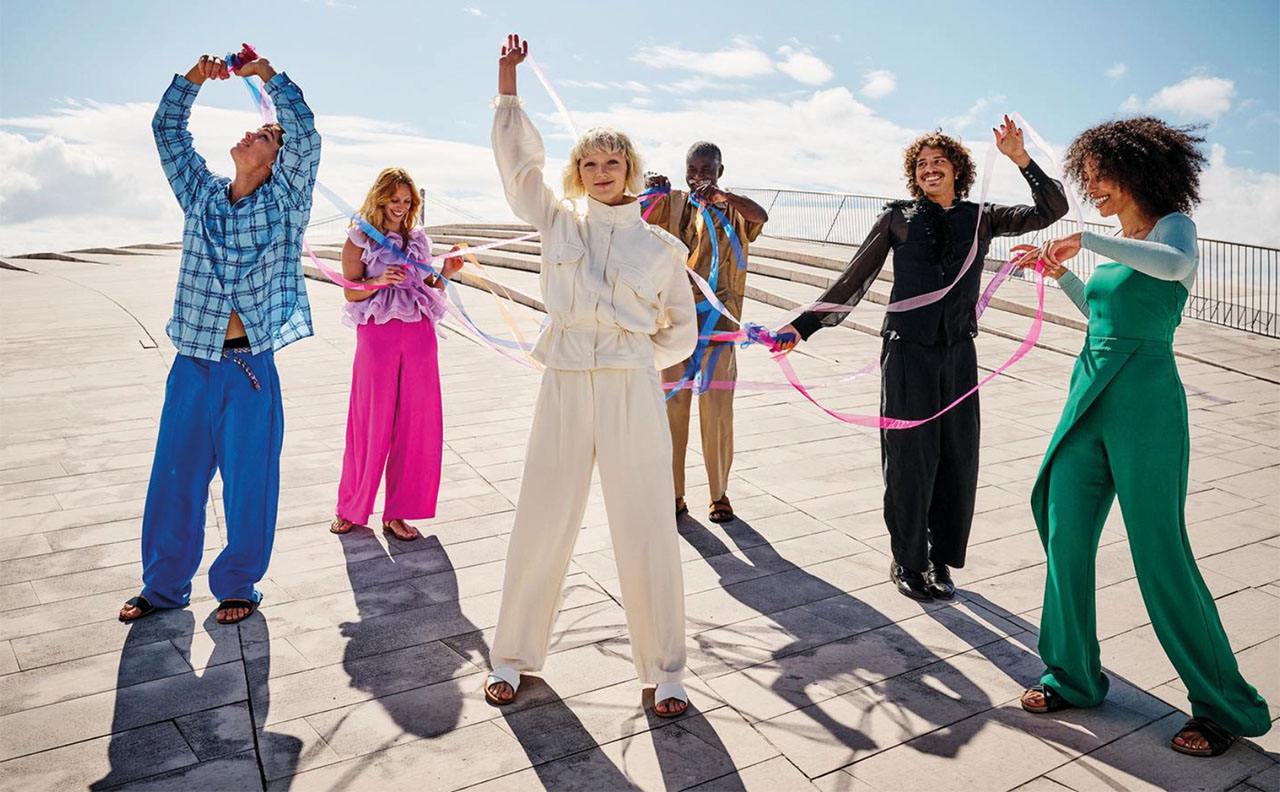 Junge Personen stehen in einem Kreis und sind mit Bändern in den Händen verbunden.