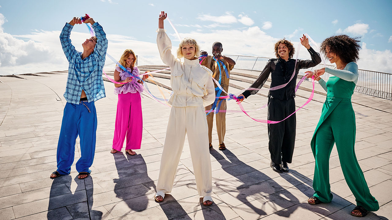 menschen in bunter Kleidung spielen mit Bändern und tanzen