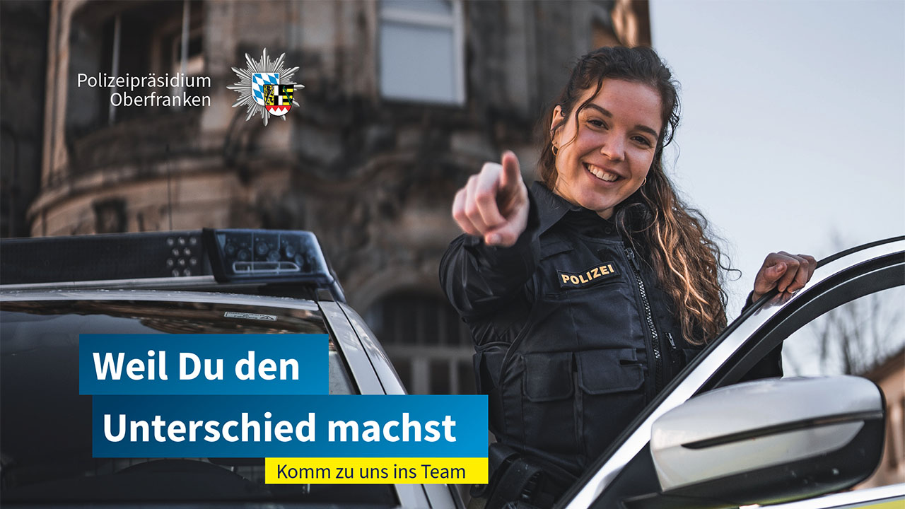 Eine Polizistin steht an einem Streifenwagen und zeigt mit dem Finger Richtung Kamera. Linksseitig der Slogan: Weil du den Unterschied machst.