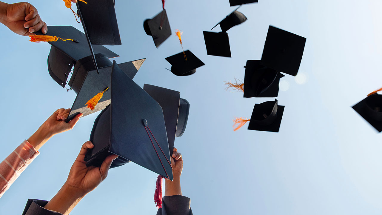 Mehrere Doktorhüte, die in die Luft geworfen werden