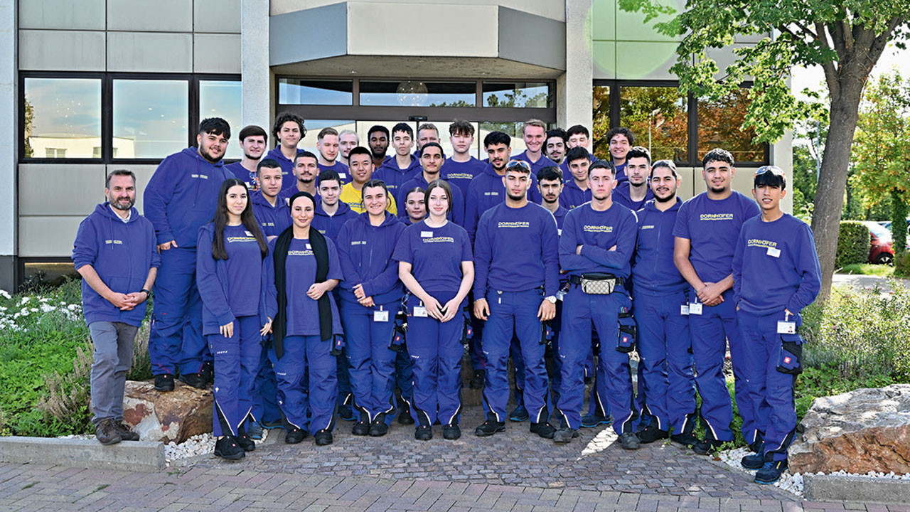 Teamfoto der Auszubildenden der DORNHÖFER GmbH in blauer Arbeitskleidung