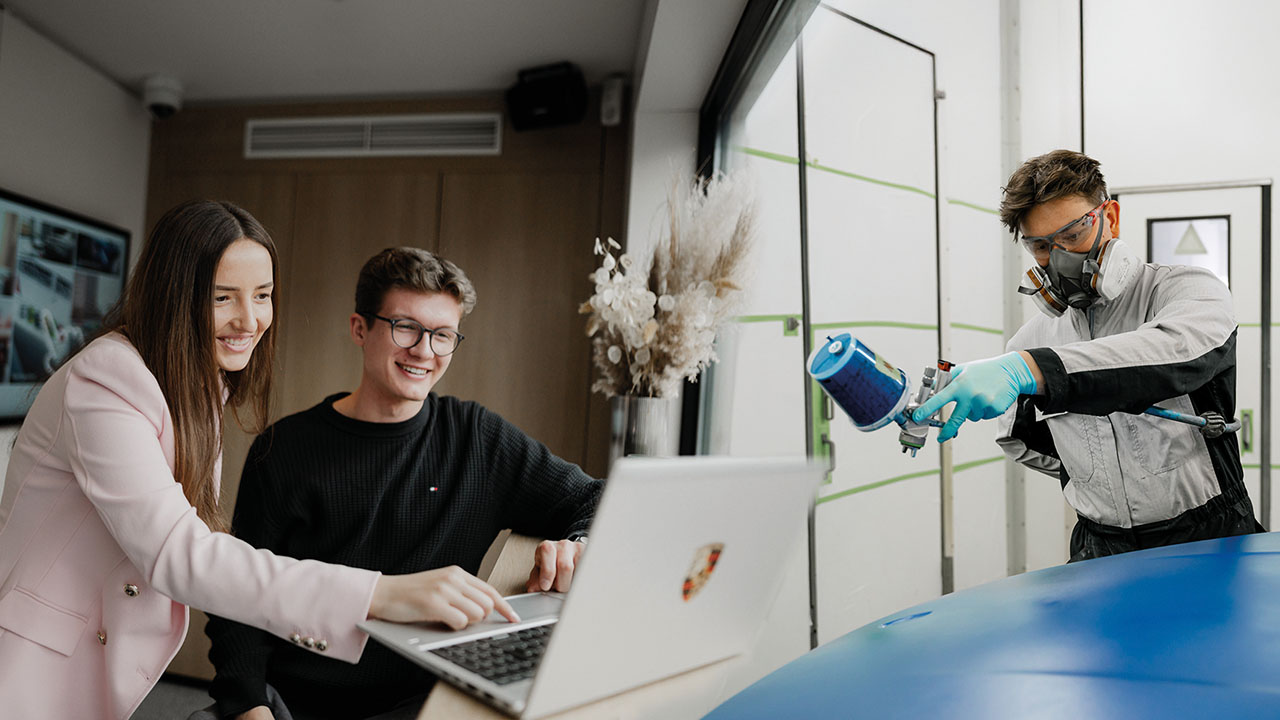 Azubis bei der Arbeit, ein Lackierer und zwei Azubis am Laptop