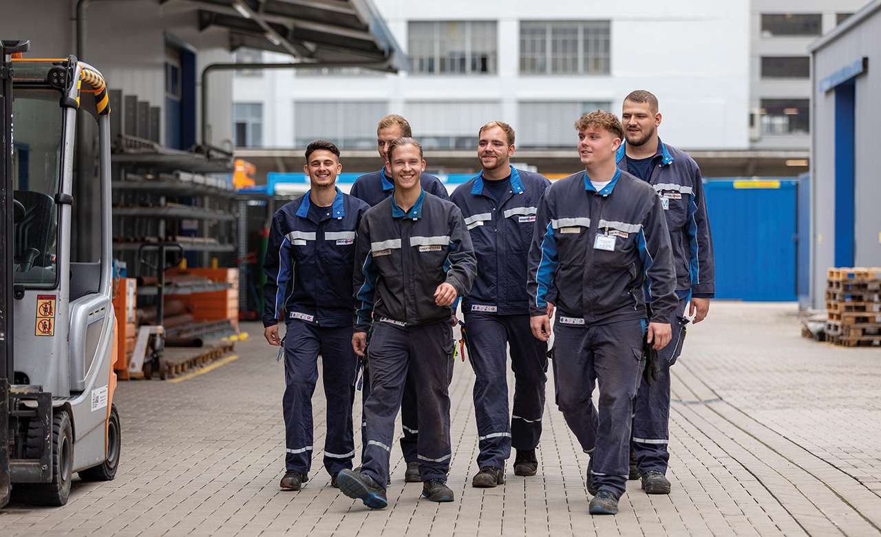 Eine Gruppe Mitarbeitern in Arbeitskleidung in einer Maschinenhalle