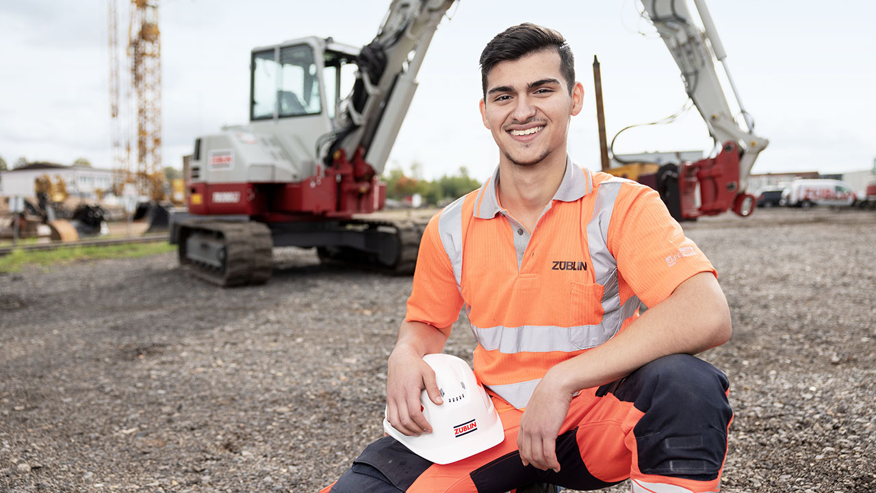 Junger Mensch auf einer Baustelle lächelt in die Kamera