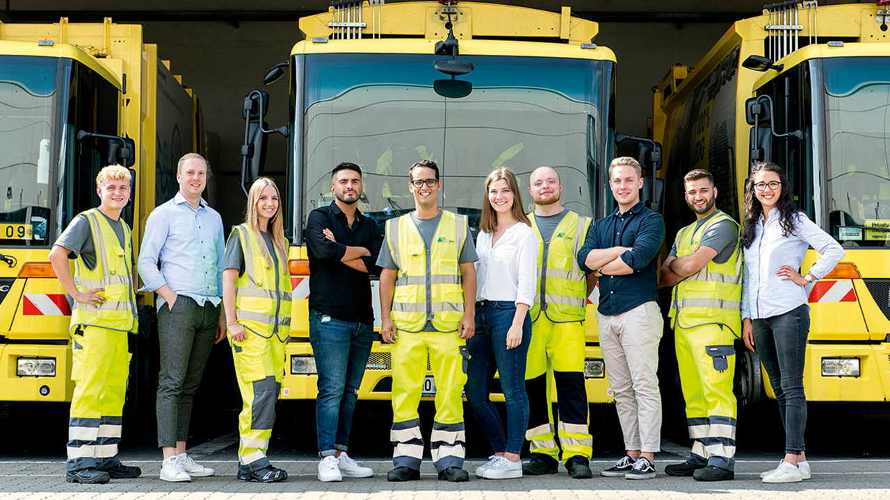 Gruppenfoto der Auszubildenden in Arbeitskleidung, im Hintergrund Einsatzfahrzeuge