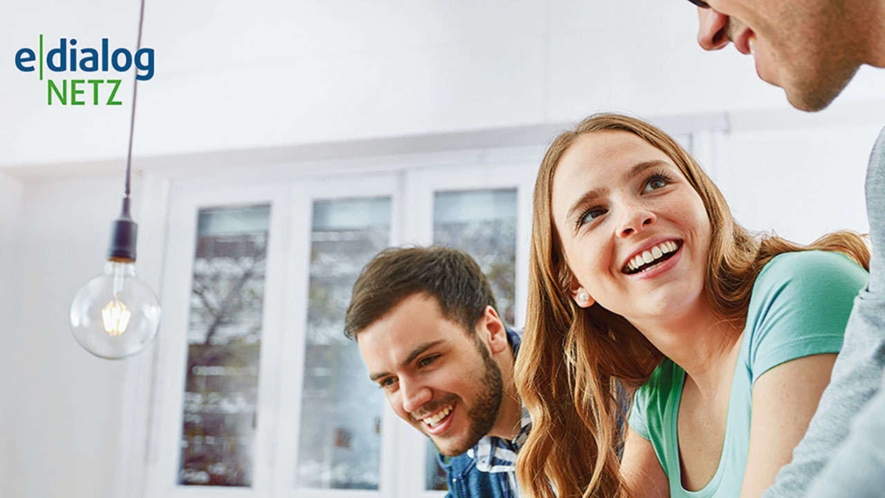 Drei Personen lächeln sich an. Im Hintergrund ist eine Fensterfront zu sehen. In der linken oberen Ecke ist das Logo der e.dialog Netz GmbH.