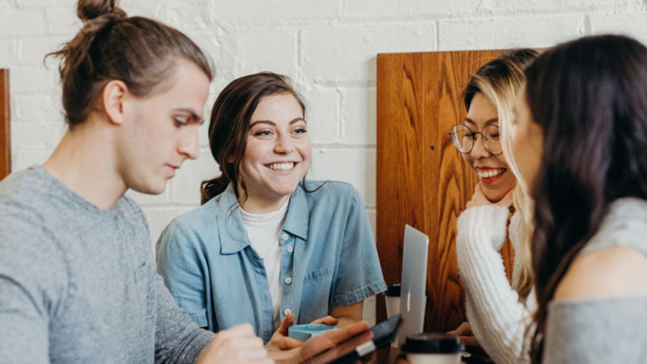 Vier junge lächelnde Personen im Gespräch