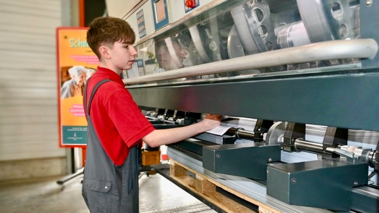 Auszubildender bei der Arbeit an einer großen Druckmaschine