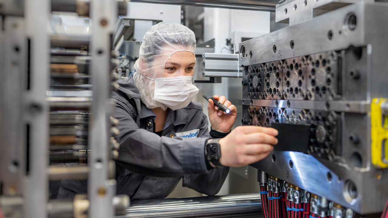 Junge Frau mit Schutzatemmaske und Haarschutz bei der Arbeit