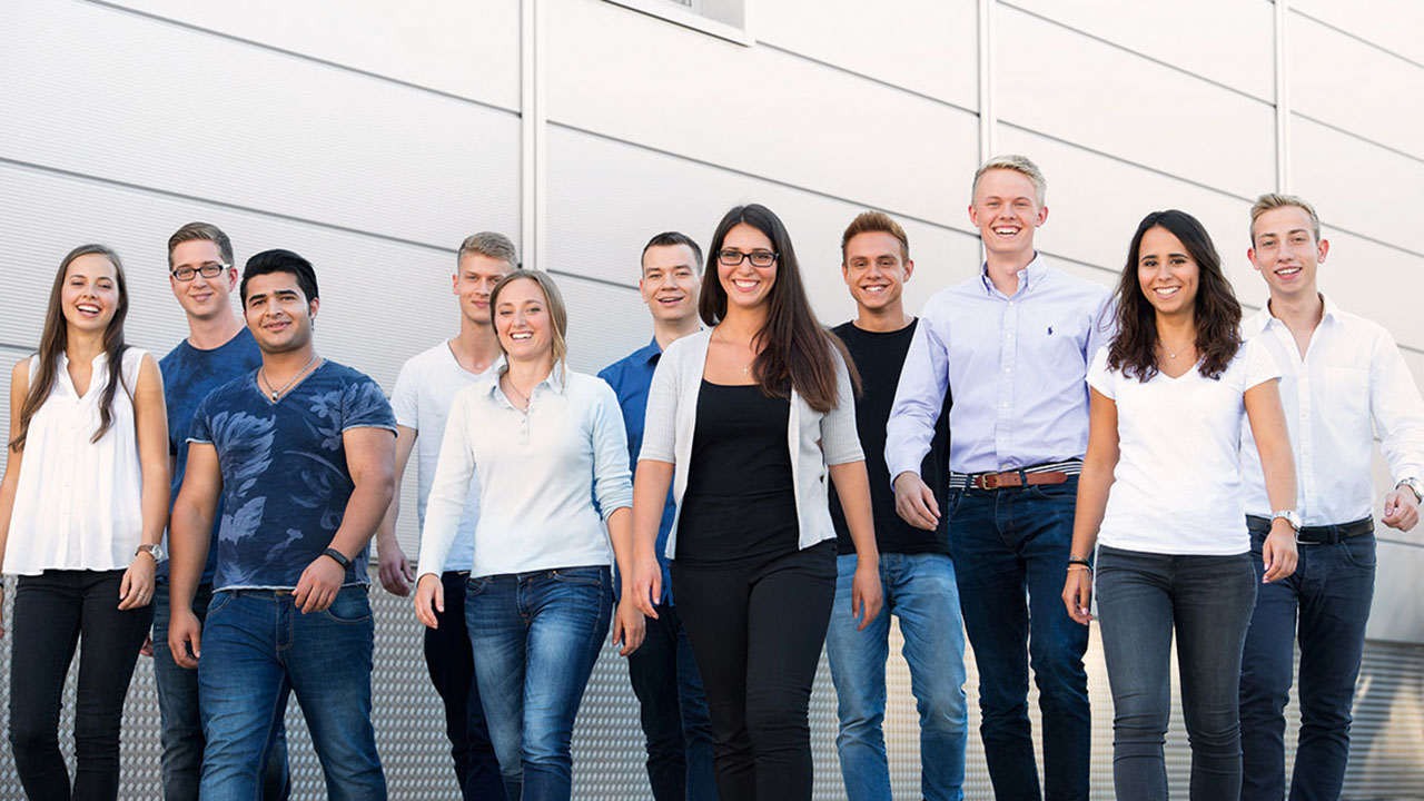 Eine Gruppe von jungen Menschen geht lächelnd auf die Kamera zu