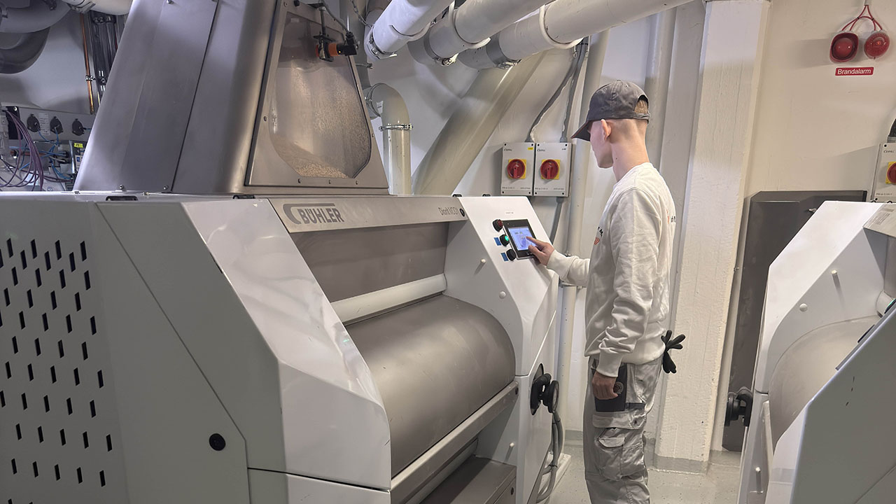 Junger Mensch in Arbeitskleidung bedient eine Maschine