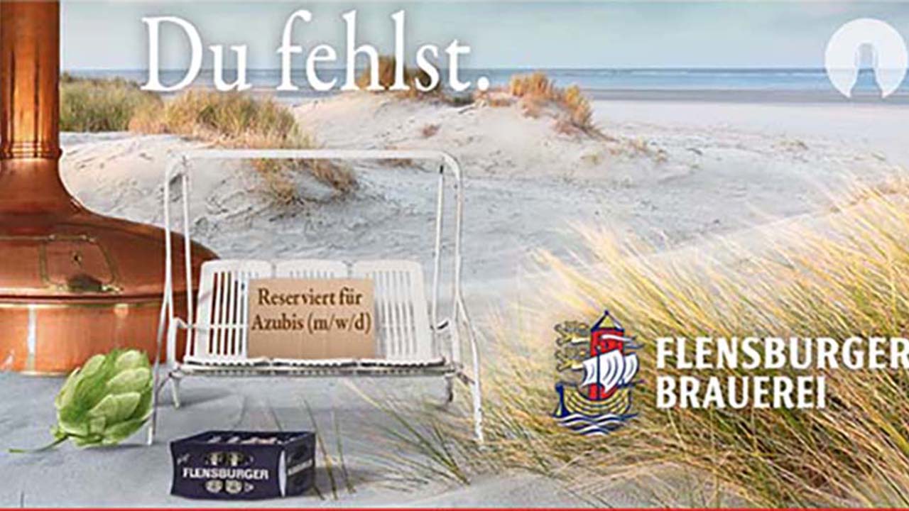 Weiße Hollywood-Schaukel vor einer Düne mit einem Schild mit der Aufschrift: Reserviert für Azubis (m/w/d). Du fehlst. Auch im Bild: Ein Kasten Bier und ein Braukessel