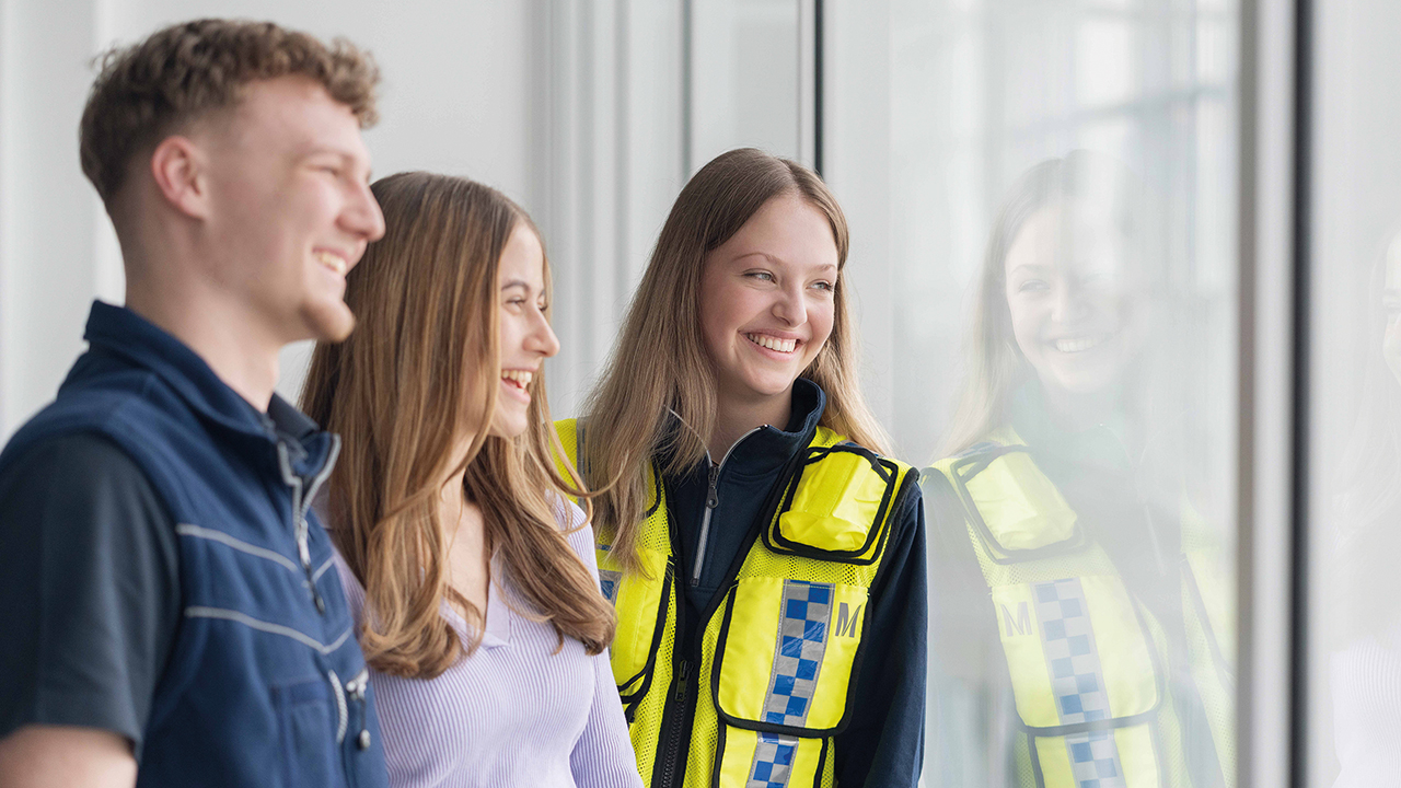 Drei junge Menschen lehnen an einer Glasscheibe. und schauen durch die Scheibe hinaus