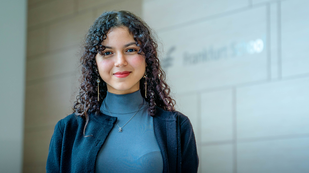 Frau vor Wand lächelt in die Kamera