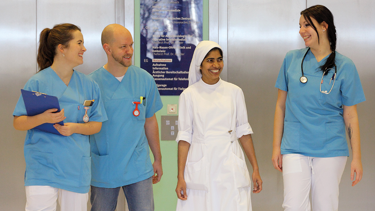 4 Pflegende auf einem Gang im Krankenhaus