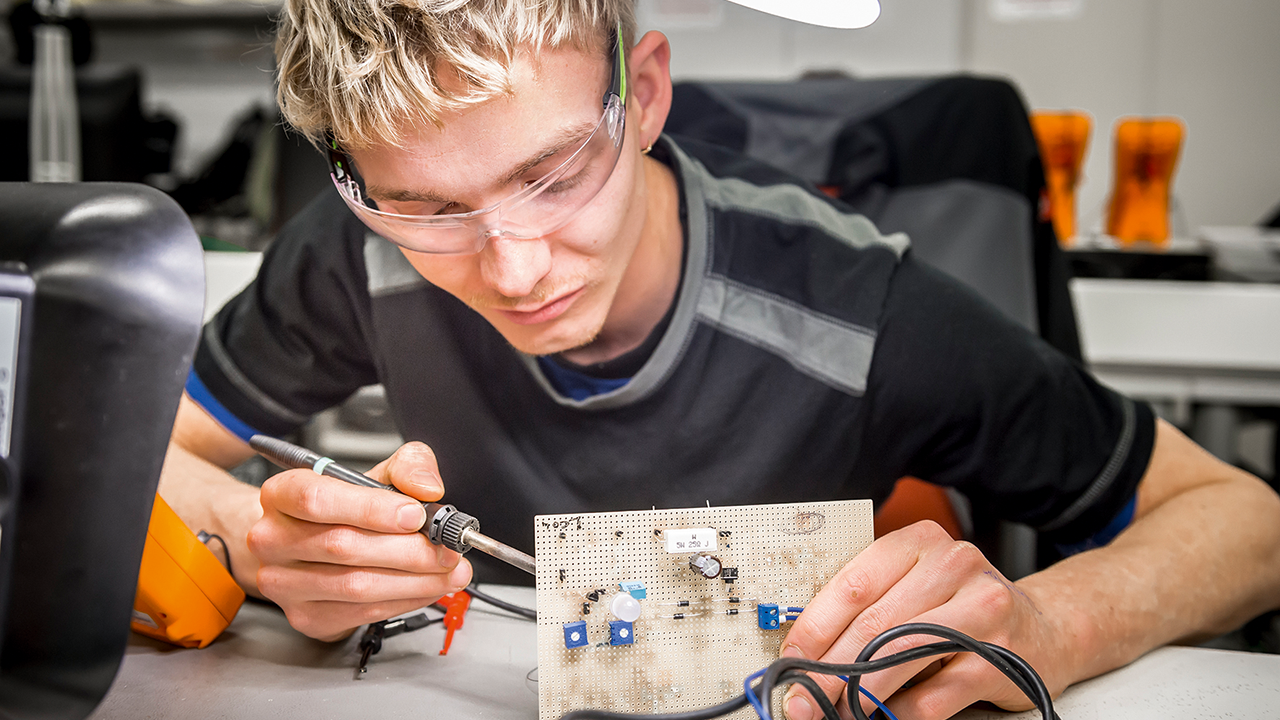 Auszubildender bei der Arbeit mit dem Lötkolben.