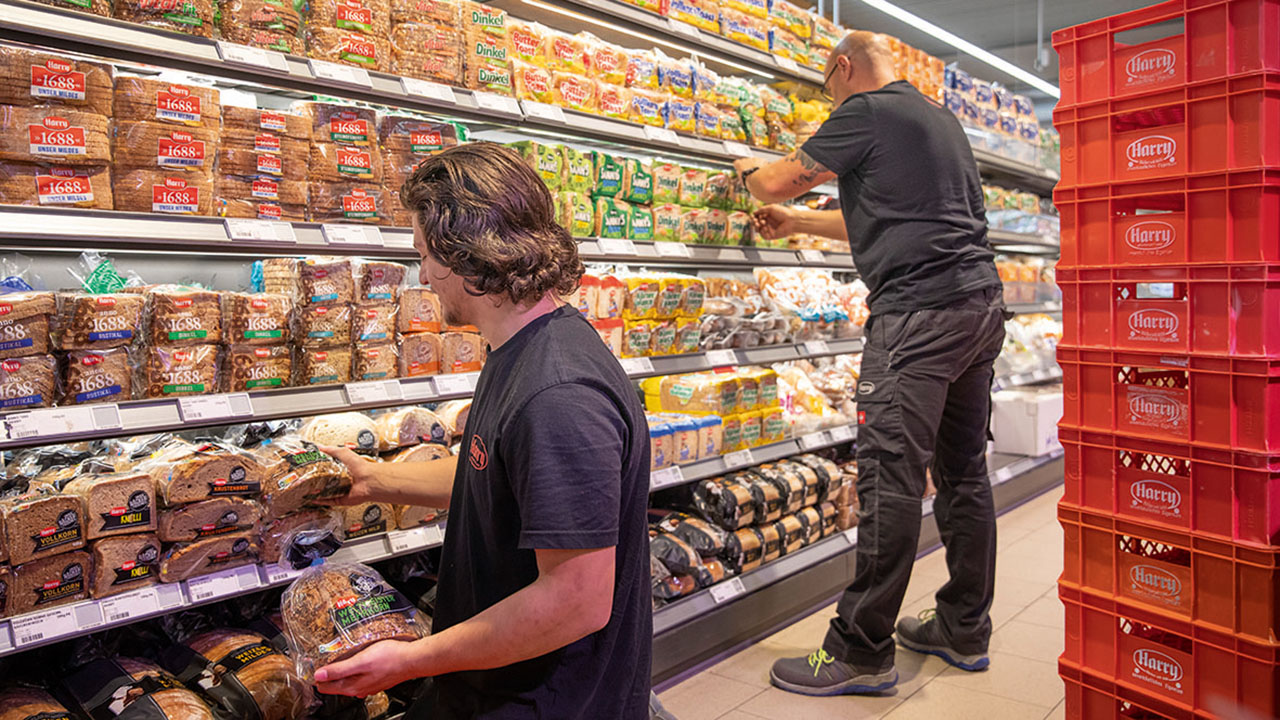 Mitarbeitende von Harry Brot beim Einräumen der Regale im Markt
