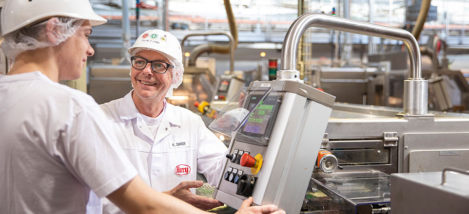 Zwei Personen stehen an Maschinen. 