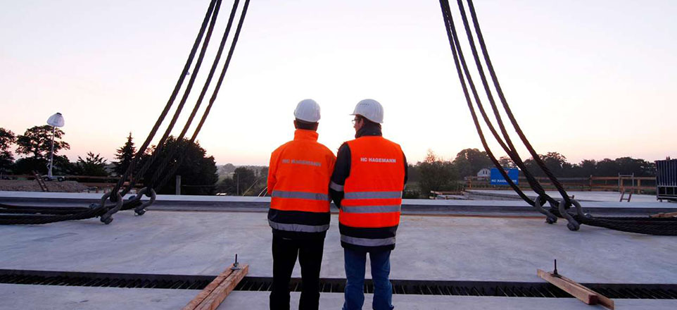 Zwei Personen auf einer Brücke die sich im Bau befindet. 