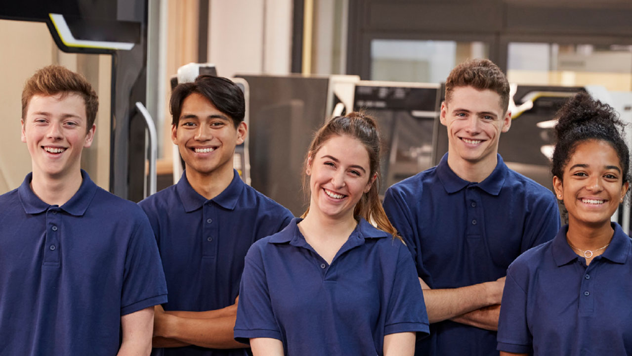 Fünf Personen in einer Halle lächeln in die Kamera.