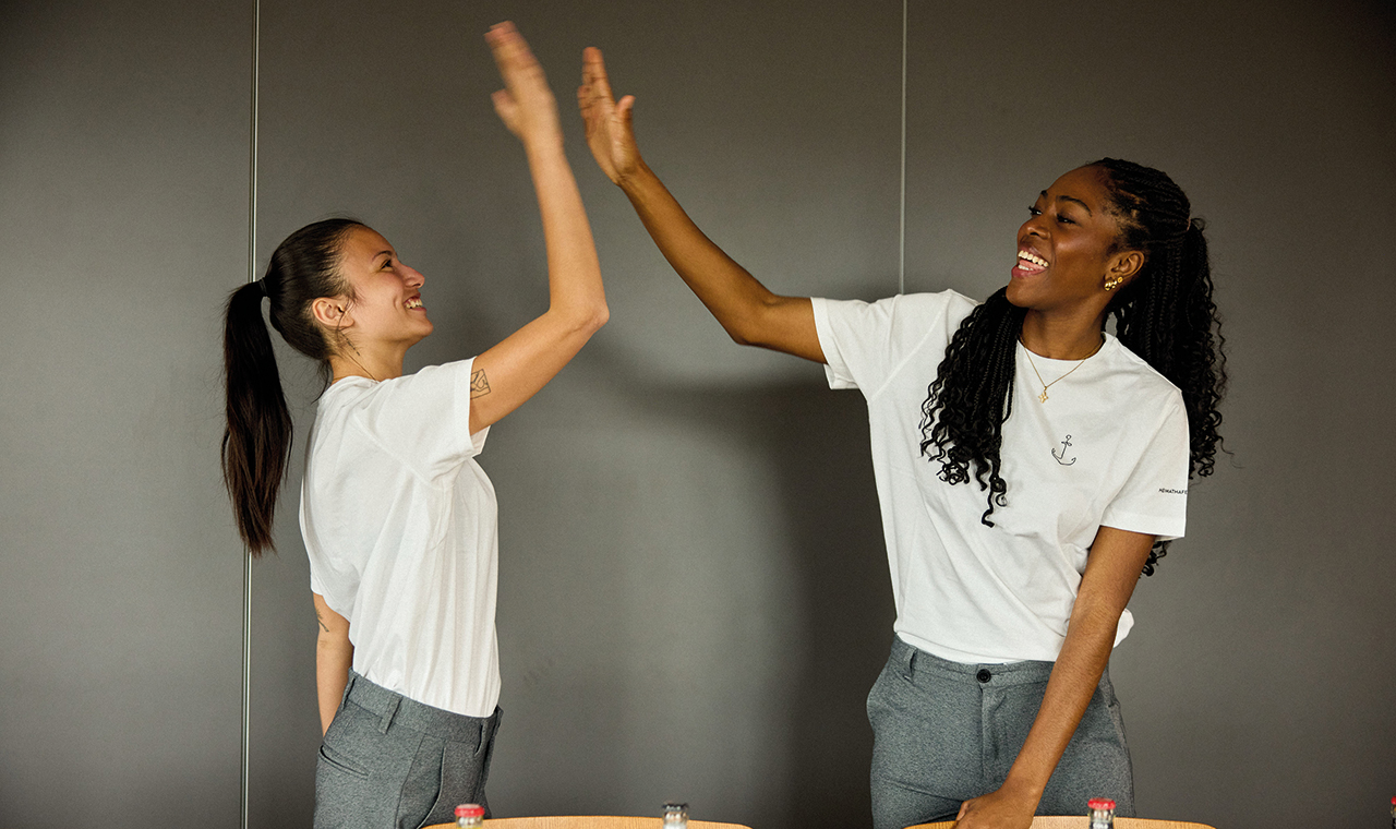 2 junge Frauen, die lachen und sich High-Five geben