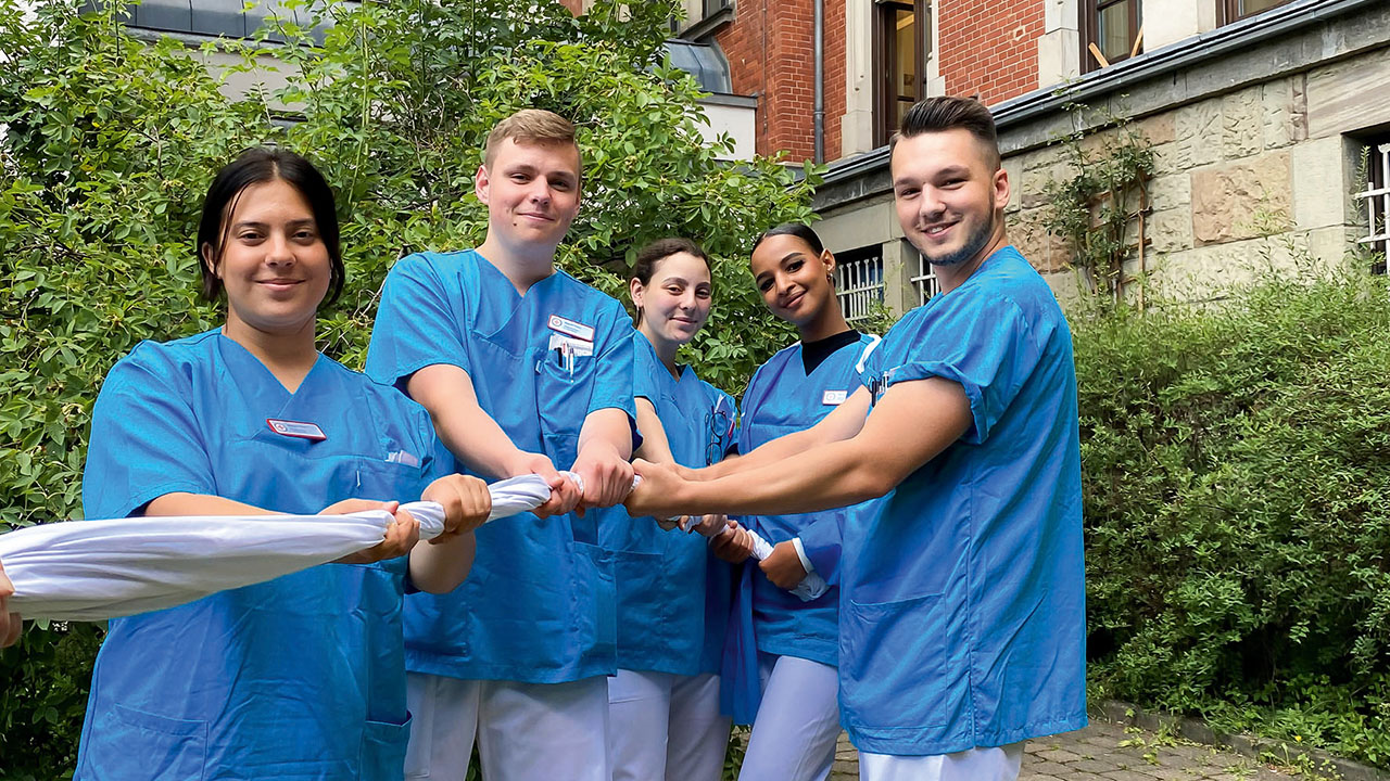 Azubis ziehen gemeinsam an einem Tuch