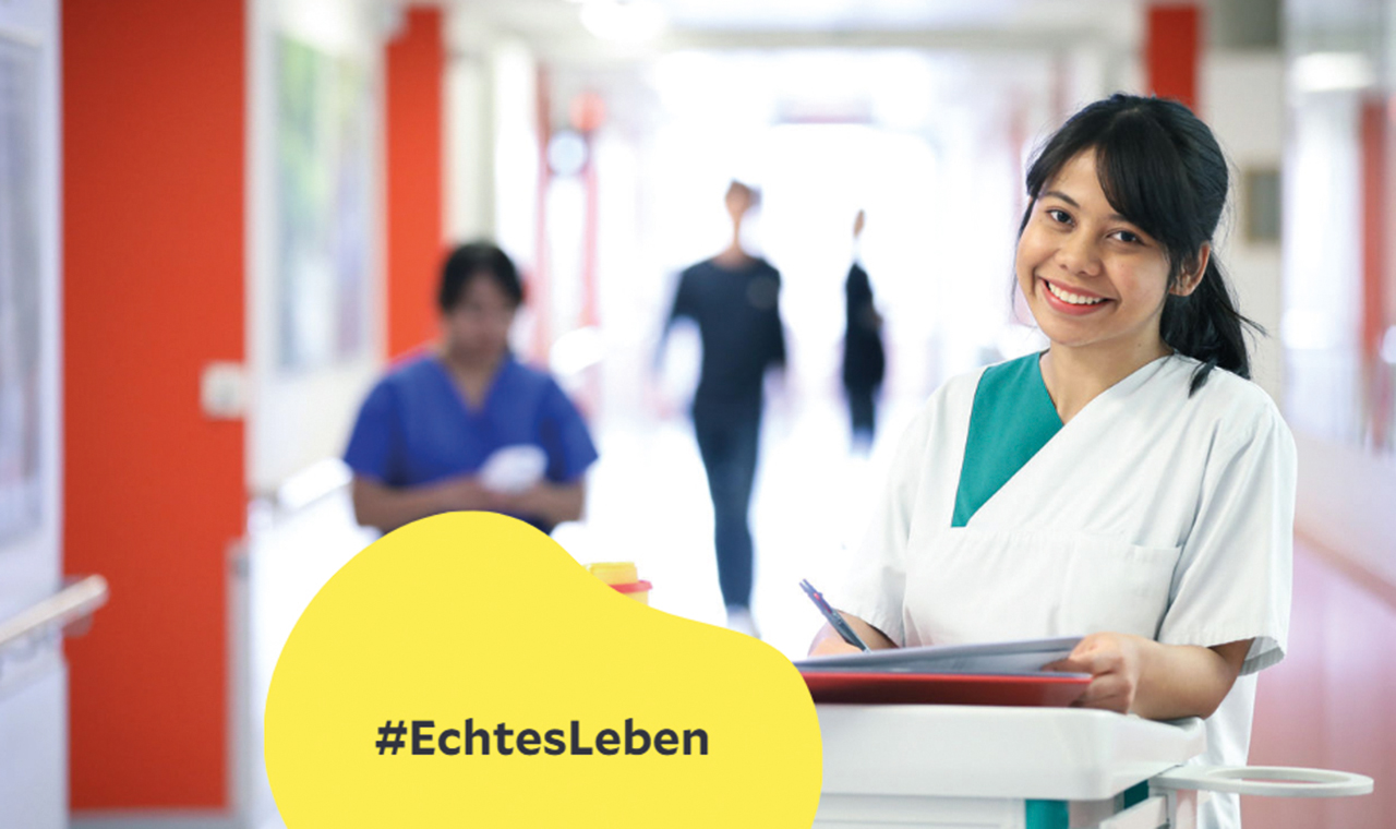 Pflegekraft lächelt in die Kamera, Schriftzug Hashtag Echtes Leben