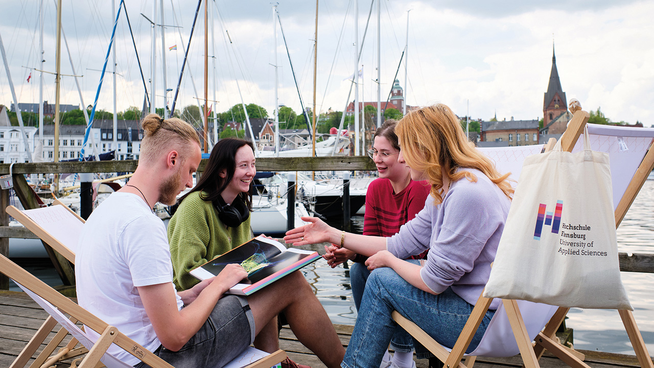 Junge Menschen die am Flensburger Hafen gemütlich beieinander sitzen