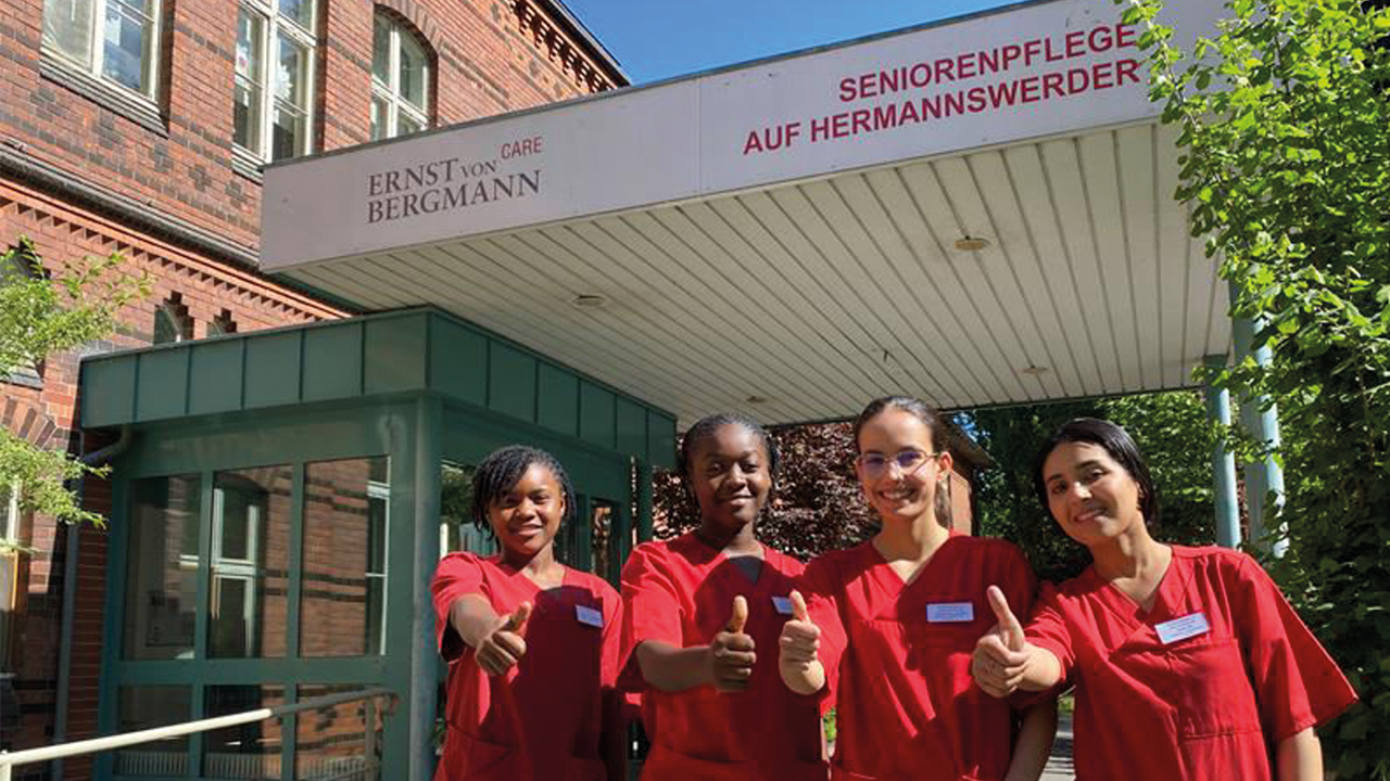 Vier Personen stehen vor der ERNST von BERGMANN CARE SENIORENPFLEGE AUF HERMANNSWERDER und halten den Daumen hoch.
