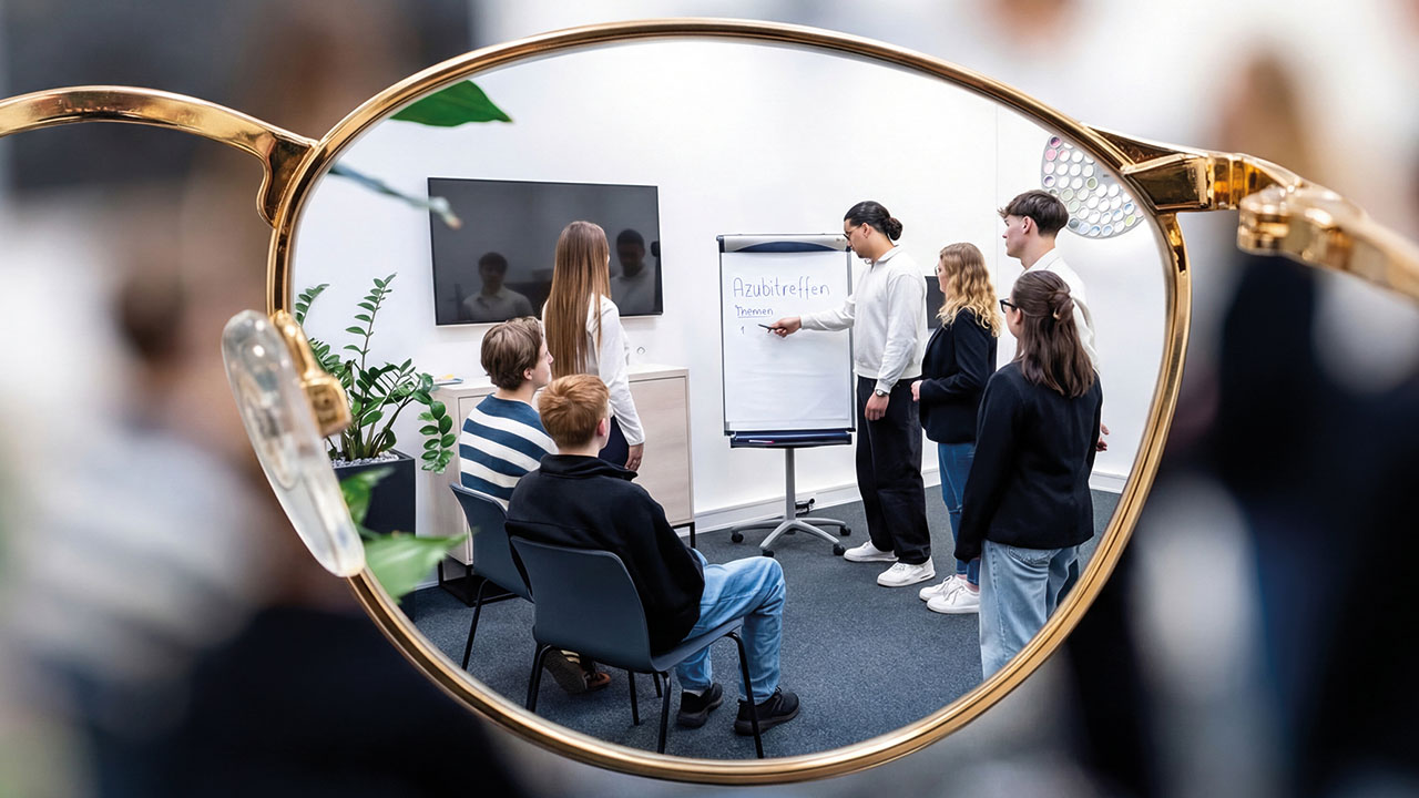 Azubis am Flipchart werden durch ein Brillenglas gezeigt.