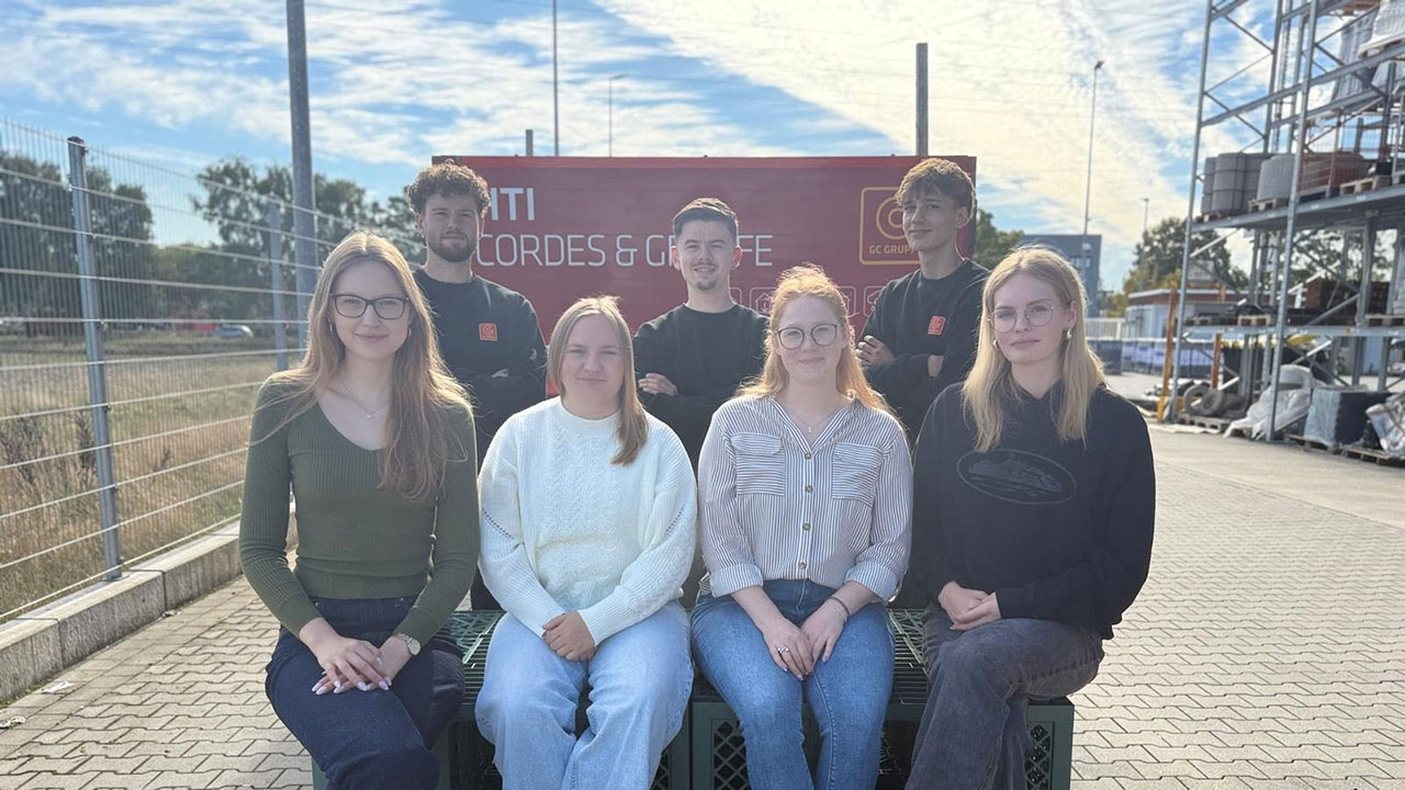 Sieben junge lächelnde Personen auf dem Firmengelände der  HTI Cordes & Graefe KG