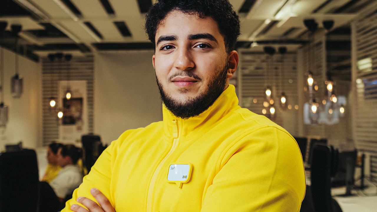 Mann in gelbem Pullover schaut in die Kamera