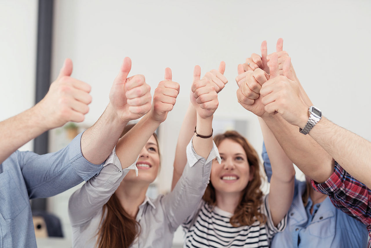 Personengruppe hält Daumen in die Luft.