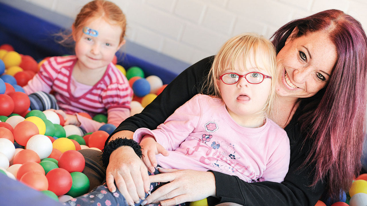 Erzieherin mit zwei Kindern im Bällebad